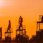 Oil pumps silhouetted against a dramatic orange sunset